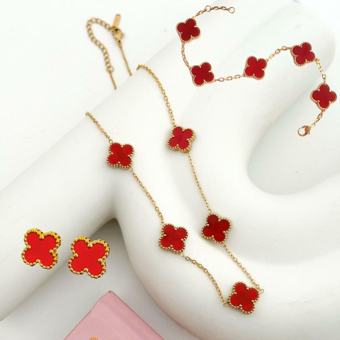 Set de joyería de trébol en tono dorado y rojo que incluye collar, pulsera y aretes a juego.