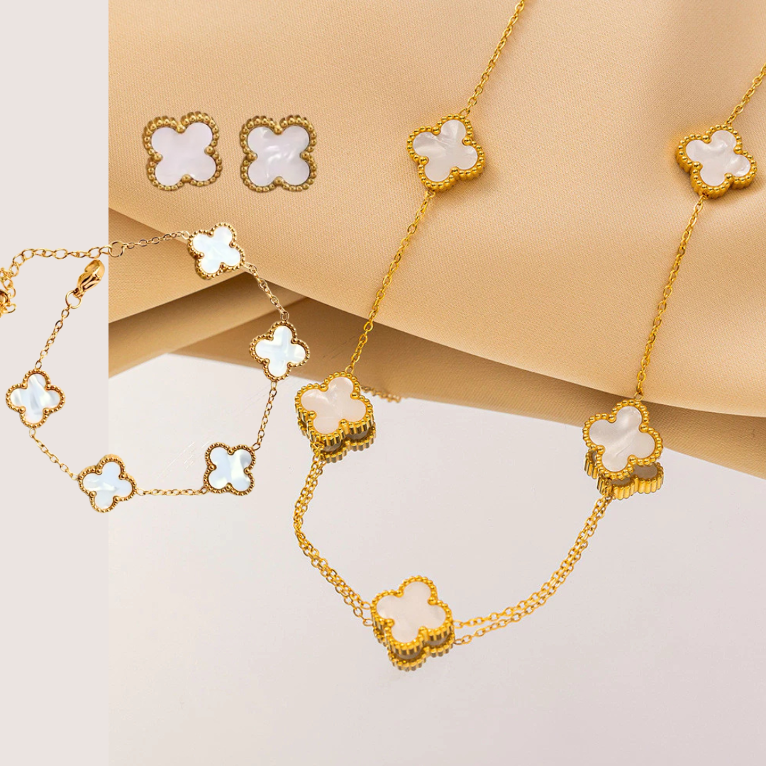 Set de joyería de trébol en tono dorado y blanco que incluye collar, pulsera y aretes a juego.