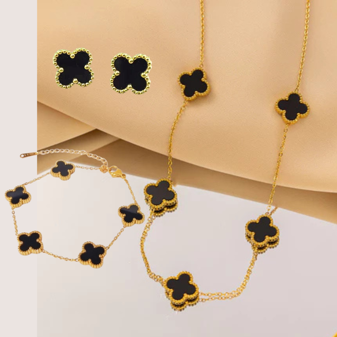 Set de joyería de trébol en tono dorado y negro que incluye collar, pulsera y aretes a juego.