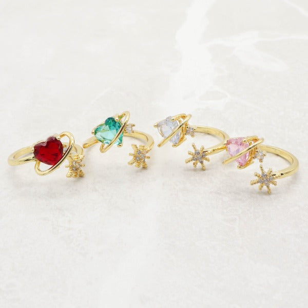 Cuatro anillos de Corazón Cósmico con piedras de colores: rojo, verde, azul claro y rosa.