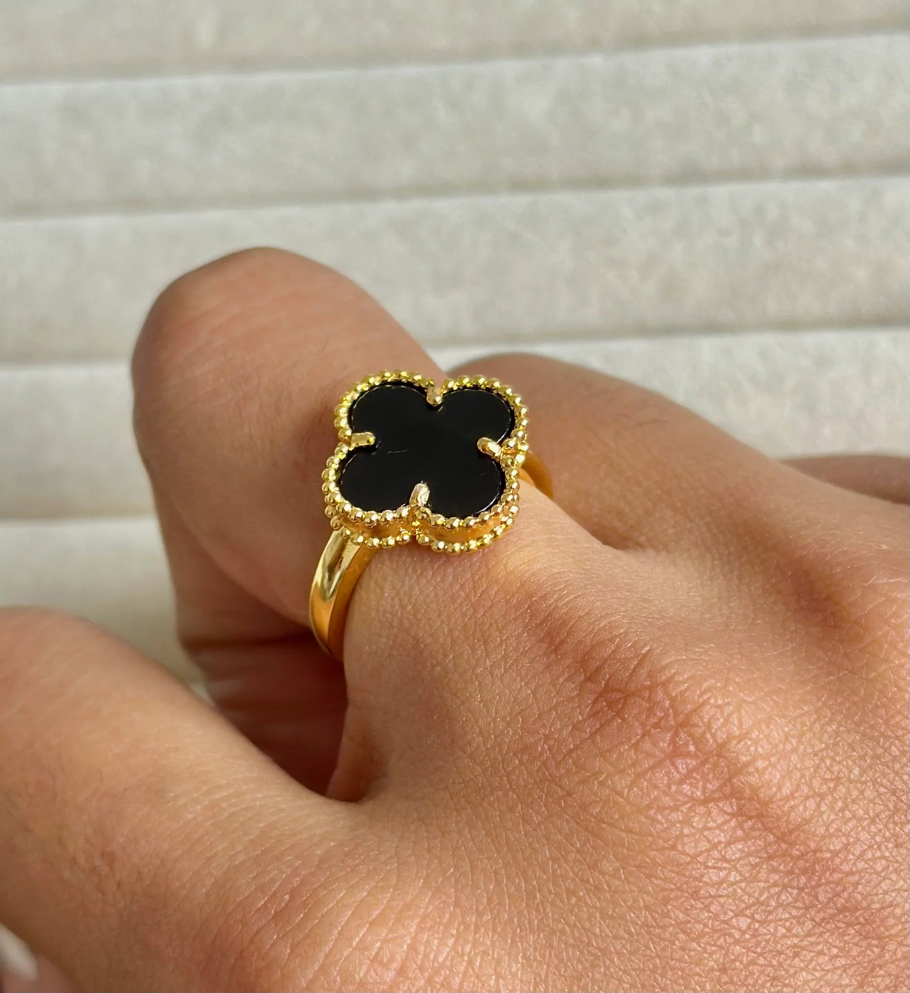 Anillo de acero inoxidable en tono dorado con un dije de trébol negro, inspirado en Van Cleef.
