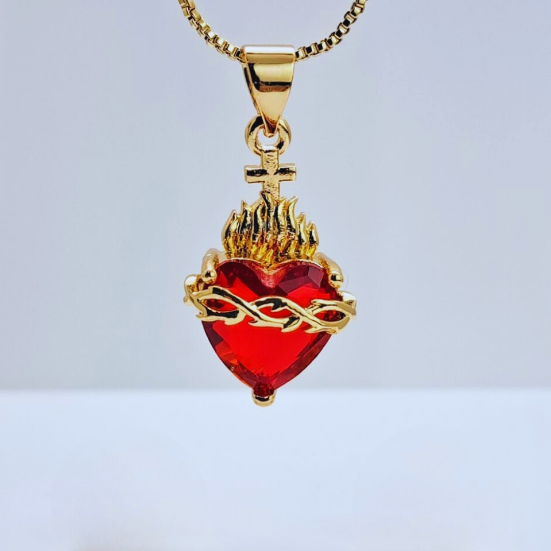 Collar con dije del Sagrado Corazón en color dorado, con un corazón central de cristal rojo, una corona de espinas, llamas y una cruz.