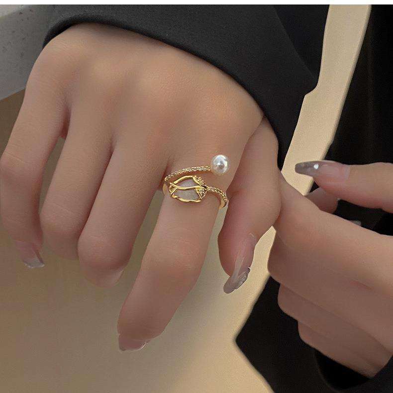 Primer plano de un anillo de flor de tulipán en color oro, mostrando el detalle de los pétalos y la perla.
