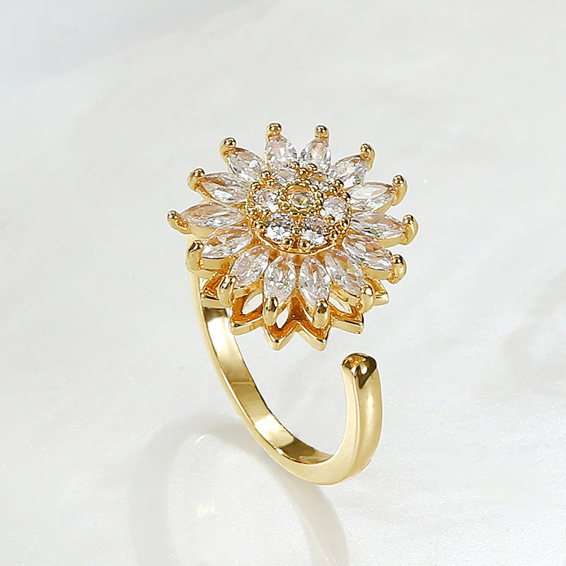 Anillo ajustable con dije de girasol giratorio en color dorado con circonias brillantes.