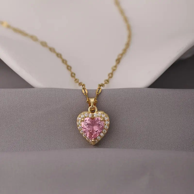 Collar con dije de corazón en color dorado, con una piedra central rosada y borde de circonias. primer plano mujer