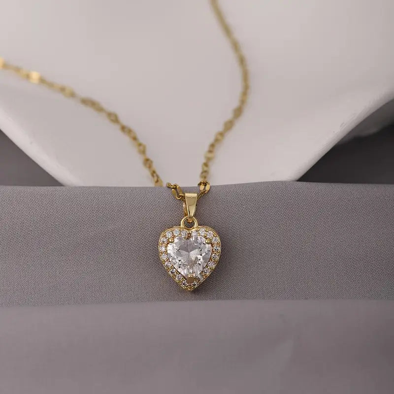 Collar con dije de corazón en color dorado, con una piedra central blanca y borde de circonias.