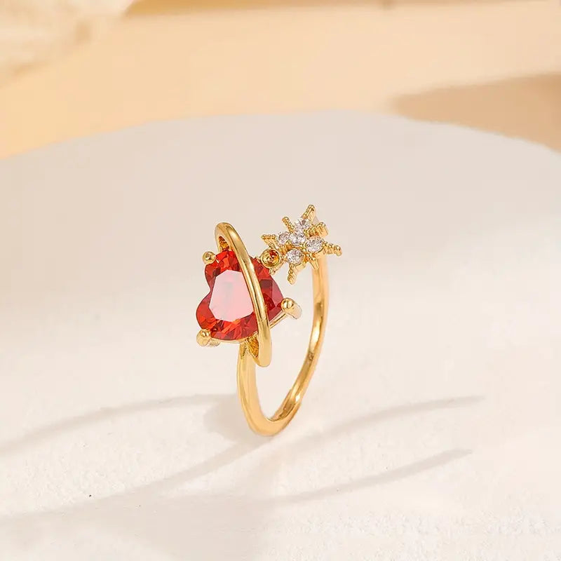 Anillo ajustable del Corazón Cósmico en acabado dorado con piedras en forma de corazón y estrellas. rojo