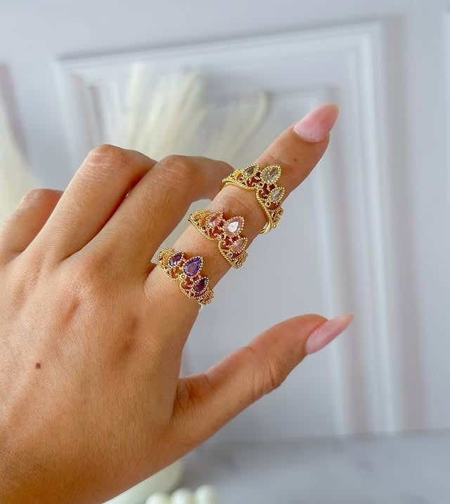 Anillo de corona de princesa Rapunzel con circones de colores fucsia, lila y blanco en el dedo.
