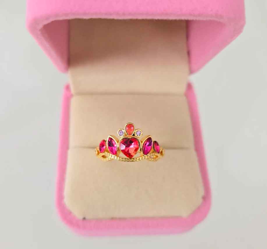 Primer plano de tres anillos de princesa de Disney, mostrando los detalles de las piedras brillantes y los cristales de colores.