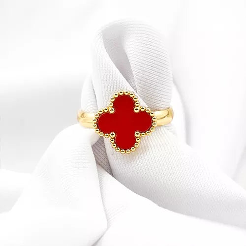 Anillo de acero inoxidable en tono dorado con un dije de trébol rojo, inspirado en Van Cleef.