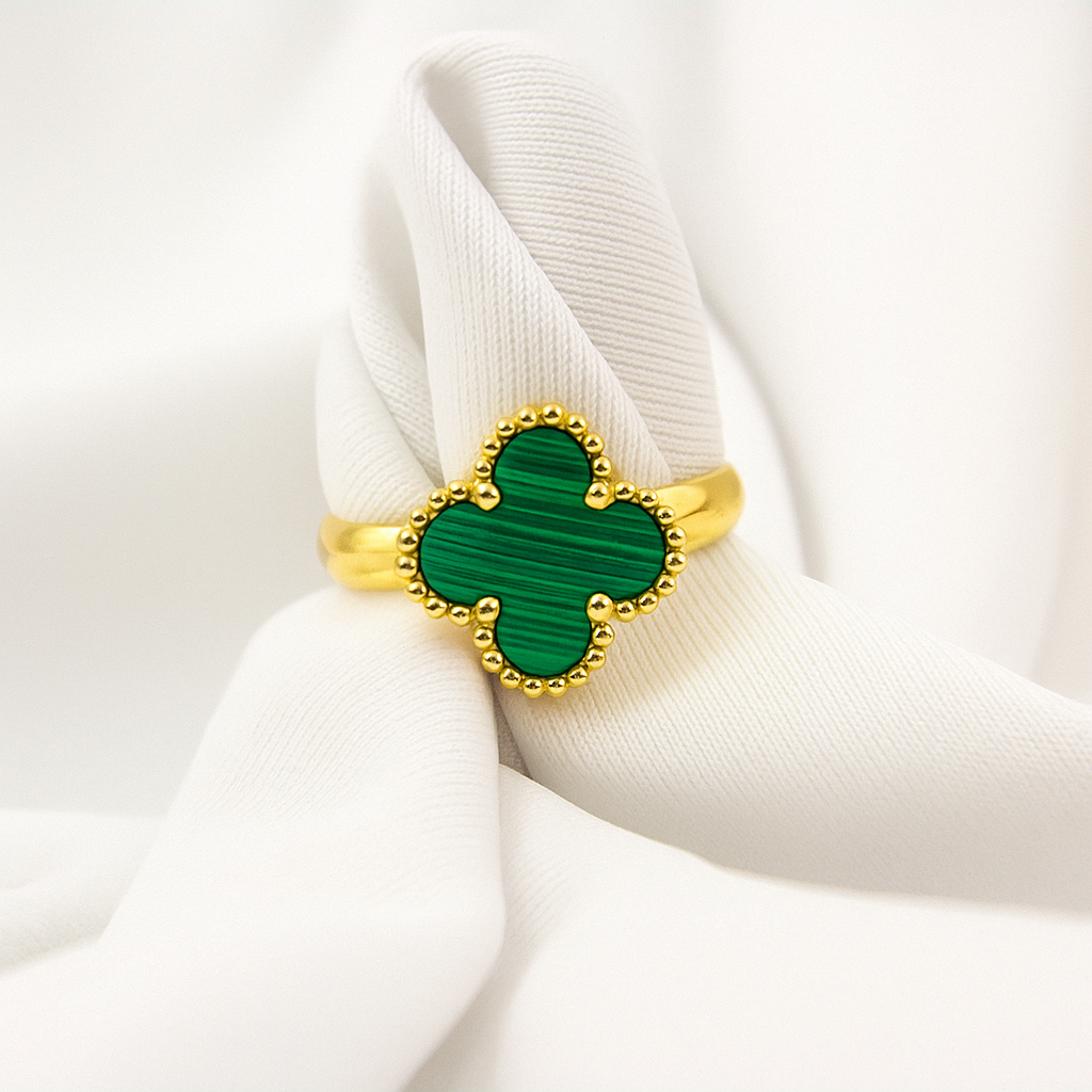 Anillo de acero inoxidable en tono dorado con un dije de trébol verde, inspirado en Van Cleef.