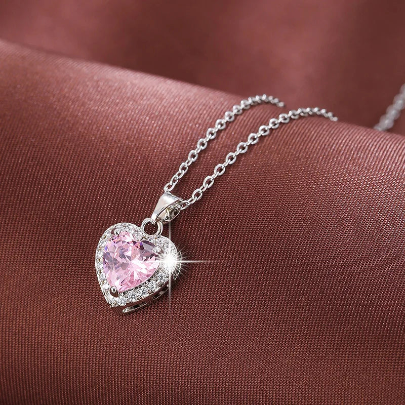 Collar con dije de corazón en color plateado, con una piedra central rosada y borde de circonias.