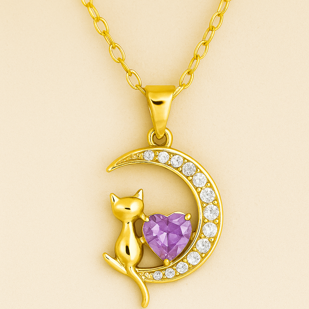 Collar con dije de gatito sentado en una luna, con un corazón central de cristal lila y acabado dorado.