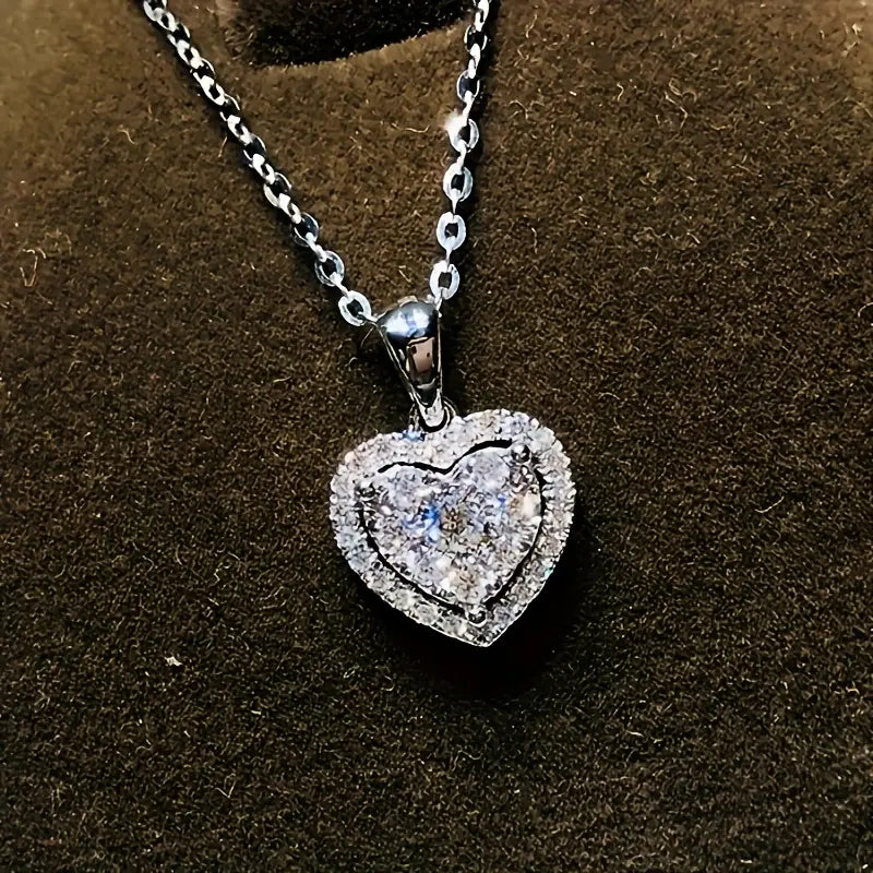 Collar con dije de corazón en color plateado, con una piedra central blanca y borde de circonias.