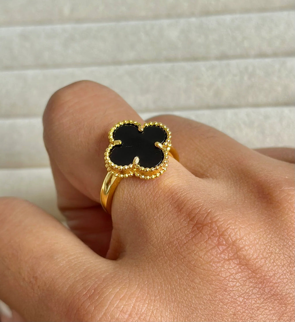 Anillo de acero inoxidable en tono dorado con un dije de trébol negro, inspirado en Van Cleef.

