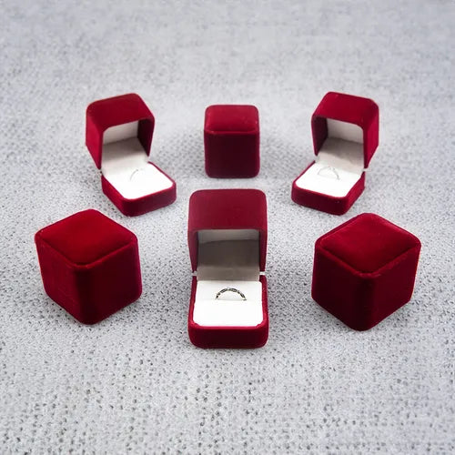 Caja de regalo de terciopelo con forma de rosa roja, abierta, mostrando un anillo en su interior.

