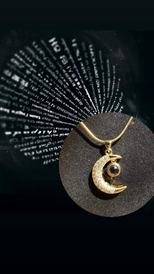 Primer plano del dije del collar de luna, mostrando el proyector de "Te Amo" en 100 idiomas y los cristales brillantes.