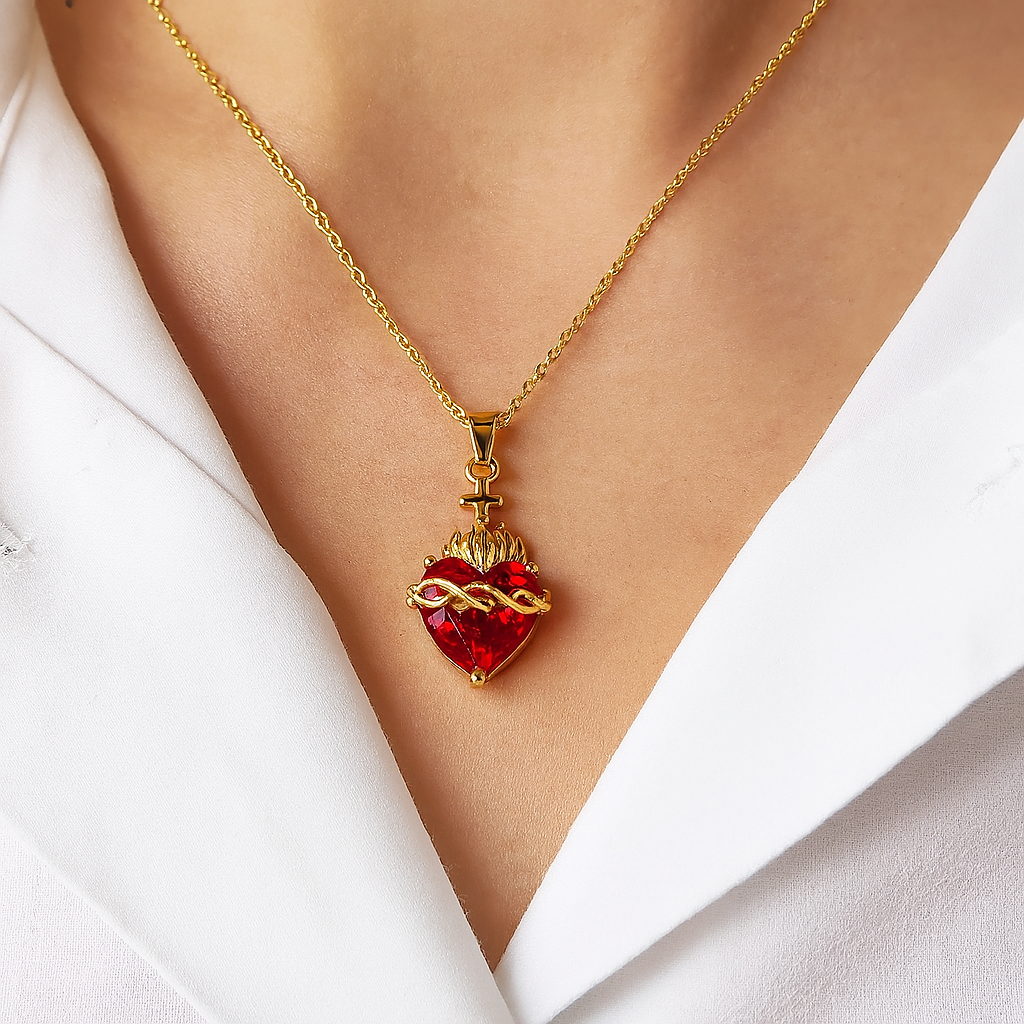 Primer plano del dije del Sagrado Corazón, mostrando el detalle de las espinas y el brillo del cristal rojo.